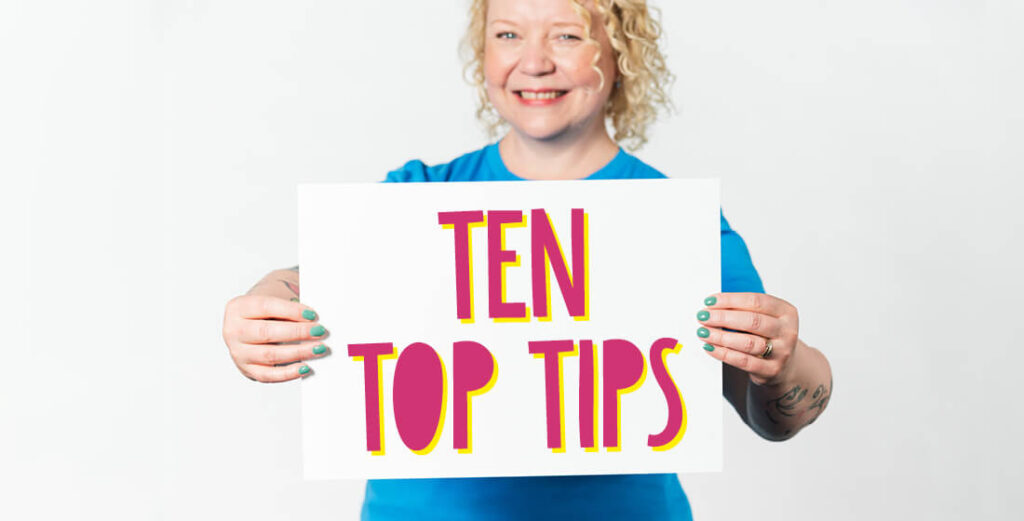 Helen Bee holding a white card with 'Ten Top Tips' written in bright pink letters.